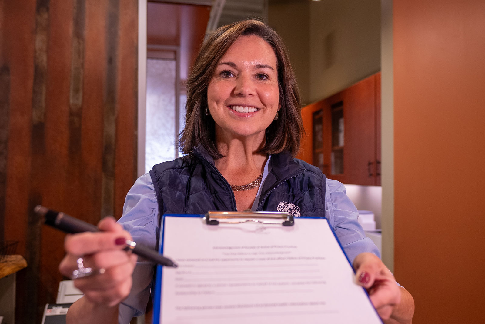 lady coordinator in blue vest with patient forms
