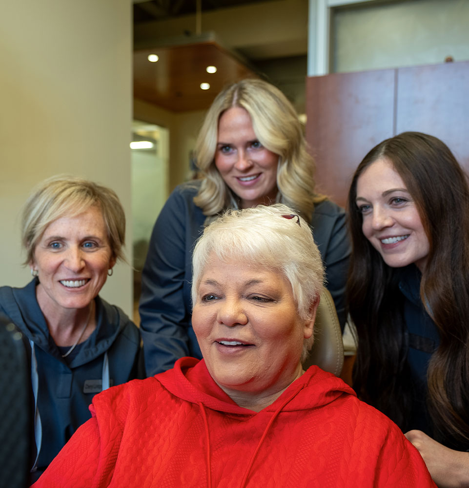 lady in red with team after her dental procedure