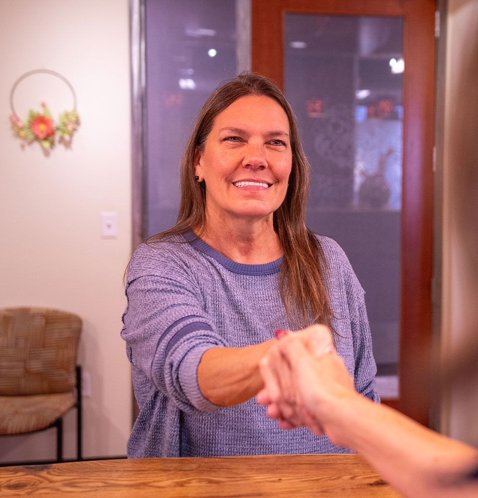 lady in blue sweater gets welcomed to dental practice