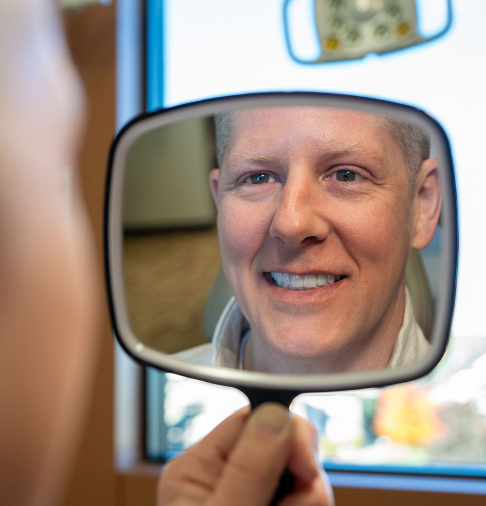 man looks in mirror full arch dental implants hero mobile